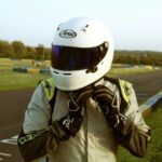 Karting racer adjusting helmet on race track in Sotteville-Sous-le-Val, France.
