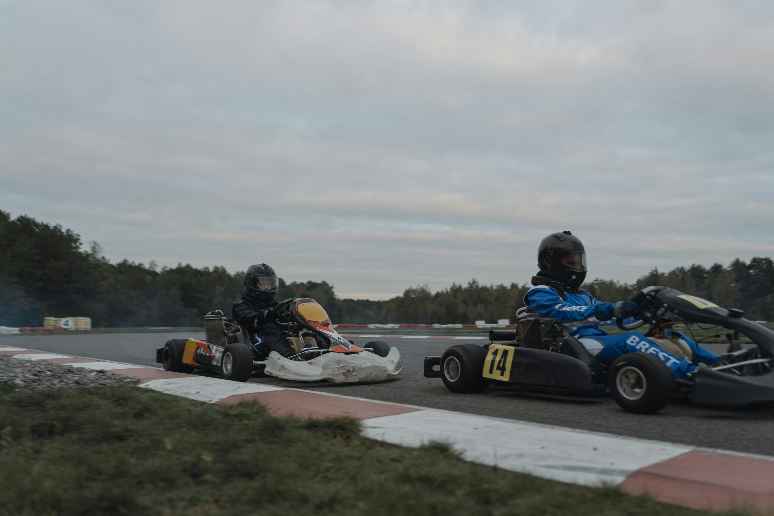 Race day excitement with two go-kart racers speeding on an outdoor track wearing protective gear.